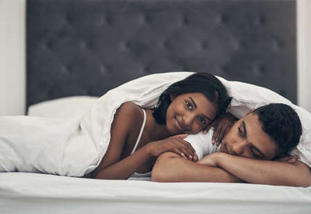 He always falls asleep before me. Shot of a young couple laying in bed at home.の写真素材