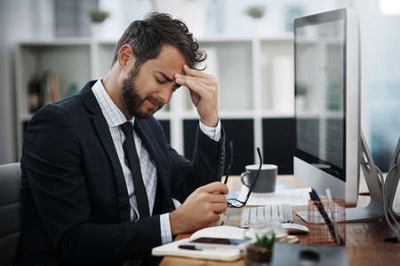The pressures of the day are driving him insane. Shot of a young businessman looking stressed out...
