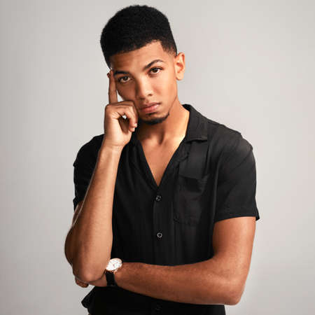 Just give me a minute to think. Portrait of a handsome young man posing against a grey background...