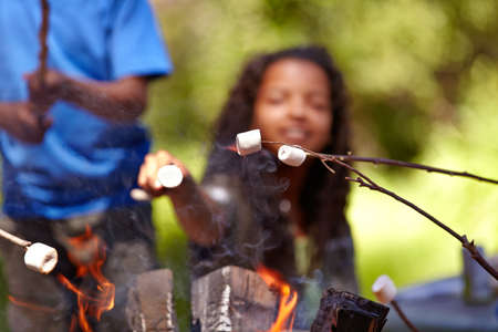 The perfect snack to enjoy with friends. Kids roasting marshmallows on an open fire.の写真素材
