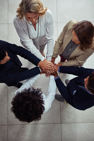 Increasing support to increase success. High angle shot of a group of businesspeople joining their...