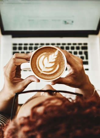 One sip inspires so many ideas. High angle shot of a young woman drinking coffee while working on a...
