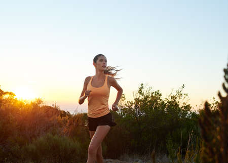 Train like a beast, look like a beauty. Cropped shot of a young woman jogging outdoors.の写真素材