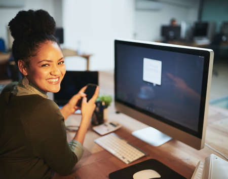 Mark this project as complete. Portrait of an attractive young woman using her cellphone in the office.の写真素材