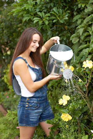 Watering her plants. An attractive young woman watering her plants.の写真素材