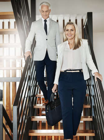 Let me take you on a tour. Portrait of two confident businesspeople walking down stairs together...