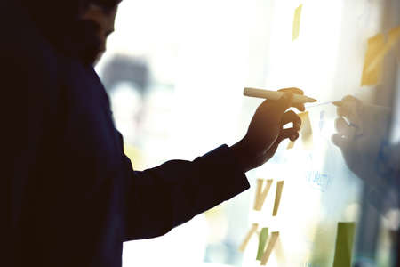 Planning is key. Cropped shot of a businessman writing notes on a glass wall in an office.