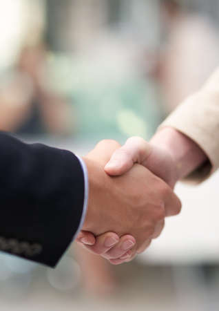 Business meetings. Shot of a coworkers shaking hands in an office.