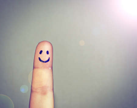 Get your happy face on. Shot of a finger with a happy face drawn on it.の写真素材