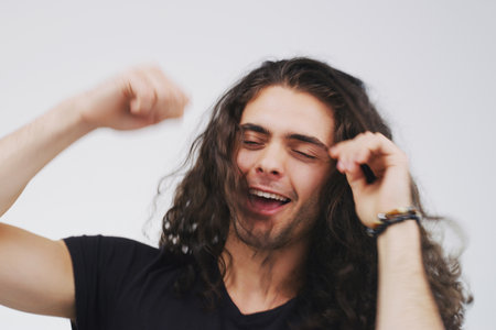 Live your best life. Studio shot of a handsome young man looking cheerful and dancing against a grey background.の写真素材