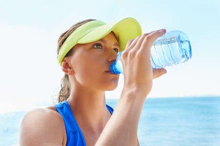 Hydration is key. An attractive and athletic young woman drinking water after a run.