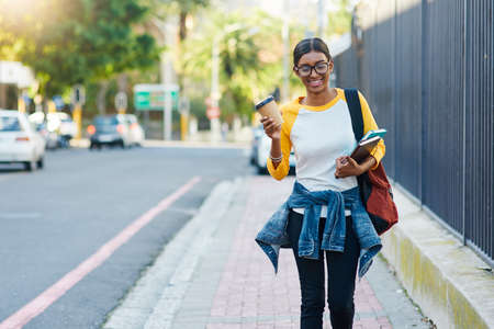 Got my coffee to commute to college. Cropped shot of a young female student commuting to college in...