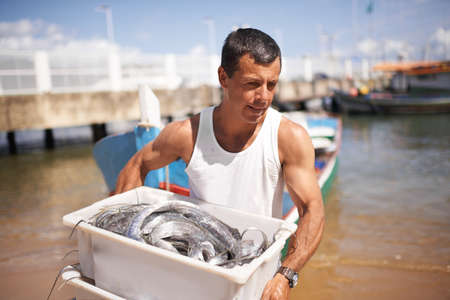 Catching fish for a living. Cropped shot of a fisherman carrying the fish he caught.の写真素材