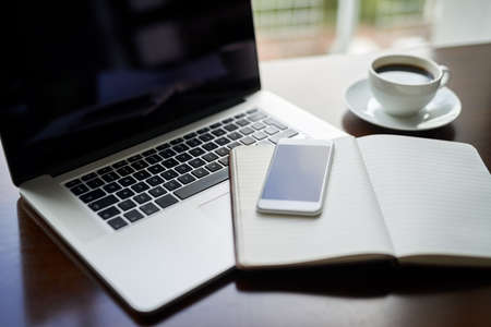 Take a seat and lets get started with success. High angle shot of a laptop, cellphone and notebook on a table.の写真素材
