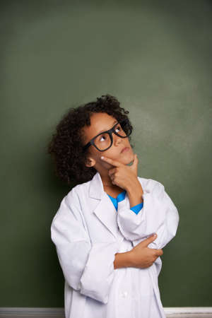 Dreaming of his bright future. An ethnic boy wearing glasses and a lab coat looking contemplative - copyspace.の写真素材