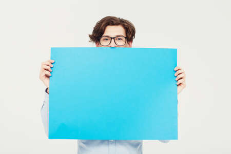 Come on over and put your copy here. A young man holding a blue placard up for your copyspace.の写真素材