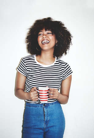 Great coffee, awesome day. Studio shot of an attractive young woman enjoying a beverage against a gray background.の写真素材