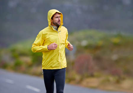 Get out there. Shot of a handsome young man running in rainy weather.
