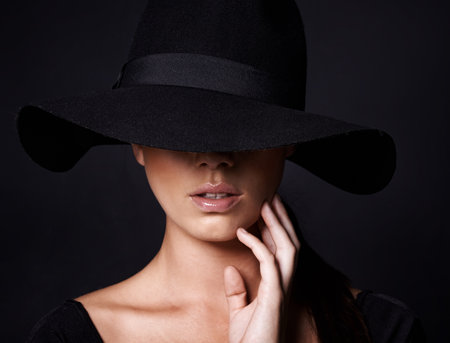 Shes a mystery youd like to unravel. Portrait of an attractive woman wearing a black hat.の写真素材