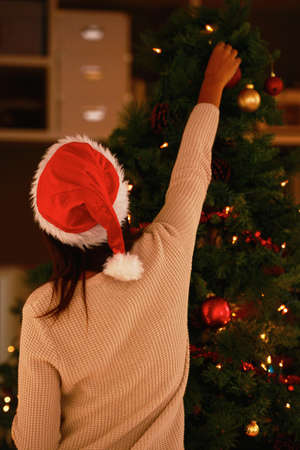 Mrs Claus always finishes off the decor with some magic. Cropped shot of an attractive young woman decorating her Christmas tree.の写真素材