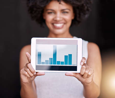 The numbers dont lie. Portrait of a smiling young business owner holding up a tablet displaying...