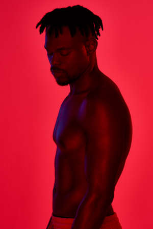 A healthy body is worth the effort. Red filtered shot of a young sportsman posing in the studio.の写真素材