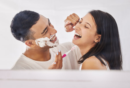 Youve got a little something on your nose. Shot of a happy young couple standing together in their bathroom and feeling playful while shaving.の写真素材