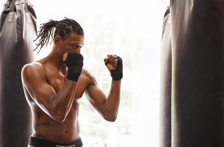 Fighting prowess. Shot of a young boxer practicing on a punching bag in a gym.