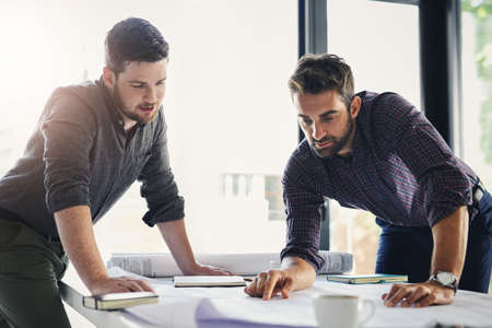 They are a two man team. Shot of two young businessmen working through business plans together...