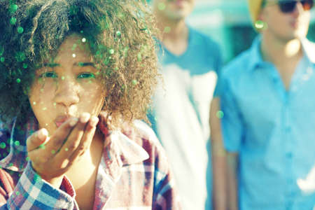 Adding a touch of sparkle to life. Young woman blowing away a handful of glitter.