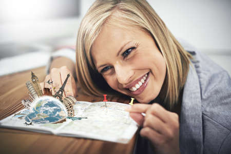 Traveling brings the world to life. Cropped shot a young woman putting pins onto a map.の写真素材