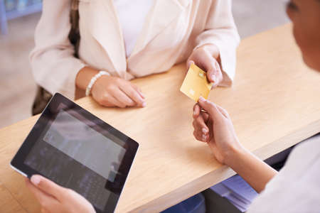 Charge it to my card. A young woman handing over her credit card to a salesperson.の写真素材