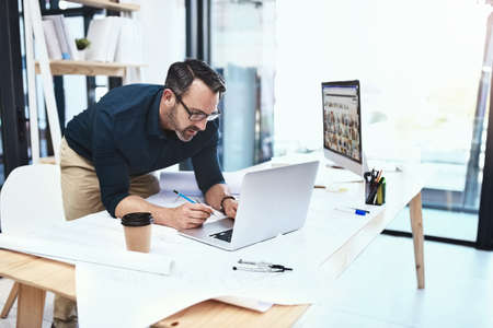 Ill find what Im looking for online. Shot of a mature male architect working on his laptop.