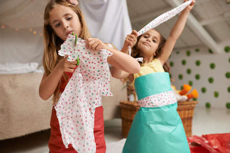 Sisters make the best friends. Shot of two little girls having fun making dresses.の写真素材