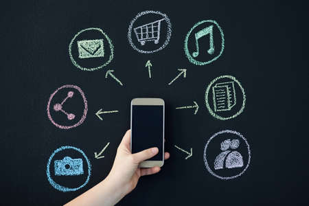 So many features to the phone. Shot of a person holding a cellphone surrounded by icons.の写真素材