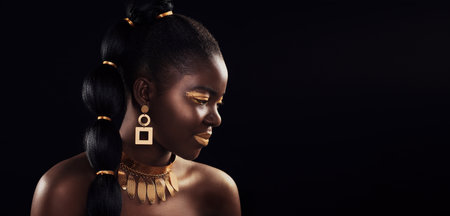 What a beauteous melanin queen. Studio shot of a beautiful young woman wearing make up and jewellery against a black background.の写真素材