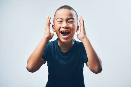 You guys...guess what. Studio shot of a cute little boy looking amazed against a grey background.