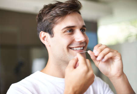 He knows the importance of dental hygiene. Closeup of a young man flossing.の写真素材
