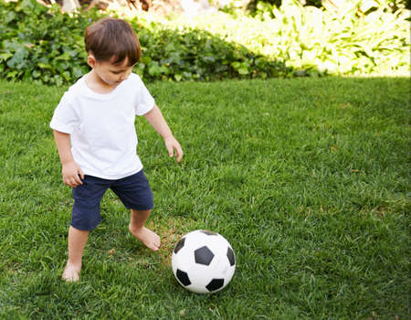 Backyard soccer. A sweet little boy with a soccer ball in the backyard.の写真素材