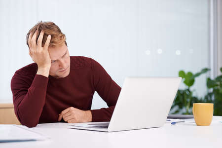 Tired of work. A handsome businessman working at his desk.