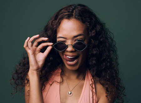 Stylishly silly. Cropped portrait of an attractive and quirky young woman posing against a green background in studio.の写真素材