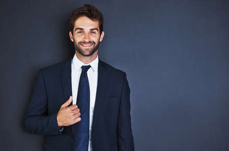 Make success a habit. Studio portrait of a handsome young businessman standing against a grey background.の写真素材