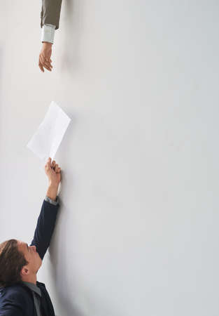 Team support. Shot of a businessman passing on a document to a colleague in an office.