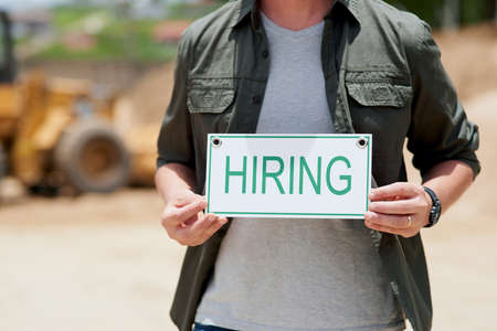 Looking for help. Cropped shot of an unrecognizable mature construction worker holding a hiring sign...