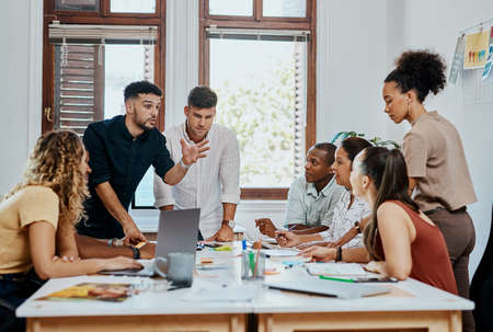 All on board for business success. Shot of a group of young businesspeople having a meeting in a modern office.の写真素材