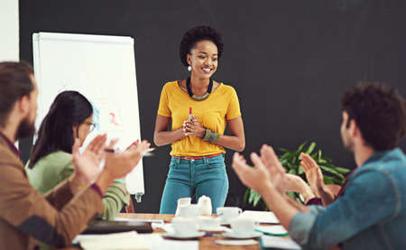 Impressing and inspiring her team. Cropped shot of people applauding together in an office.の写真素材