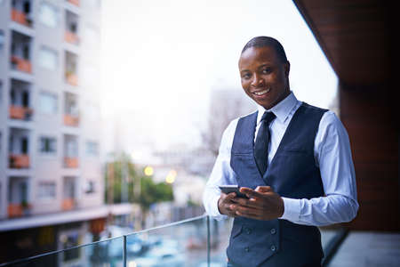 Stepping out to make a call. Cropped shot of a well-dressed businessman standing on a balcony.の写真素材