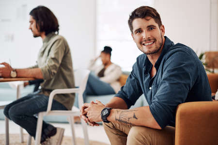 This is the team that creates success. Cropped portrait of a handsome young businessman sitting with his colleagues in the office.の写真素材