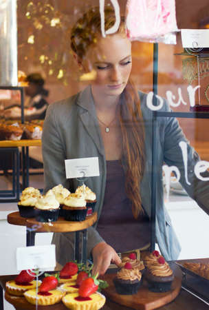 Serving only the freshest to her customers. Shot of an attractive young woman working in a bakery.の写真素材