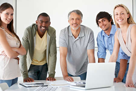 No secret to our success - teamwork. A group of businesspeople standing behind a desk with a laptop...